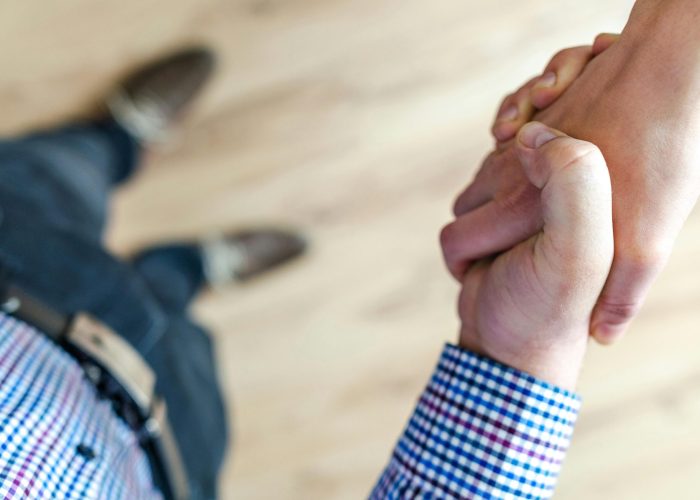 Close-up of a handshake between two people inside an office, symbolizing trust and cooperation.